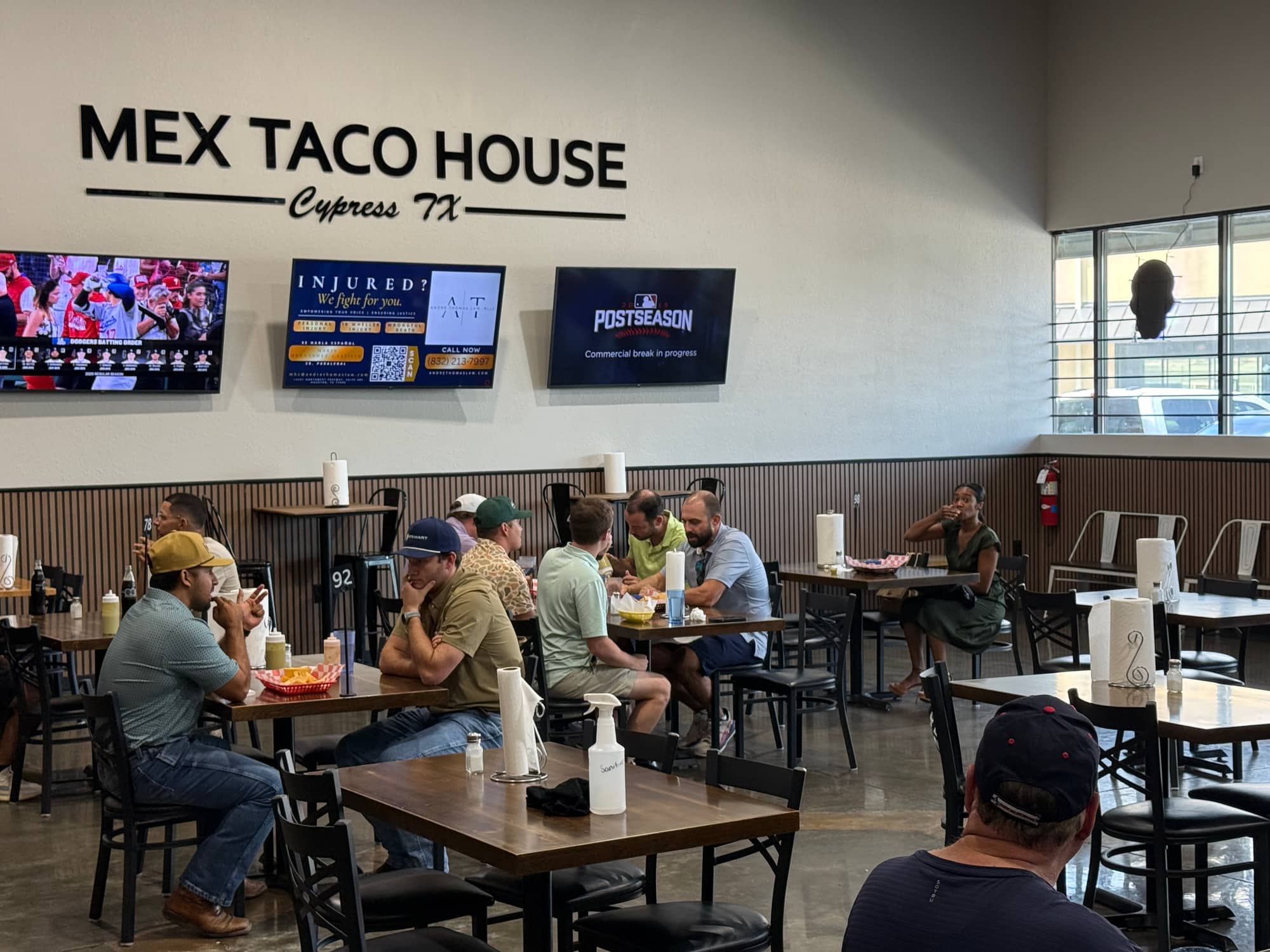 Dining room at Mex Taco House in Cypress, TX, with a client's ad playing on the wall TVs